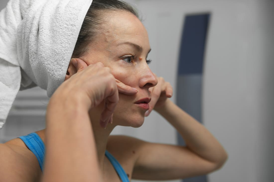 Femme regardant dans le miroir pour des problèmes de peau